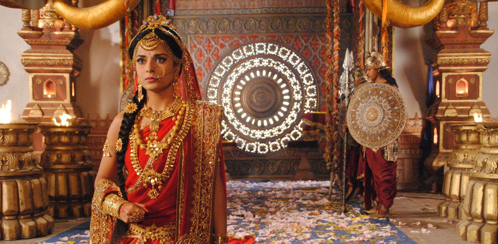 Ancient Indian queen Draupadi in royal attire with traditional jewelry and regal posture, standing in a palace courtyard with marble pillars and intricate carvings